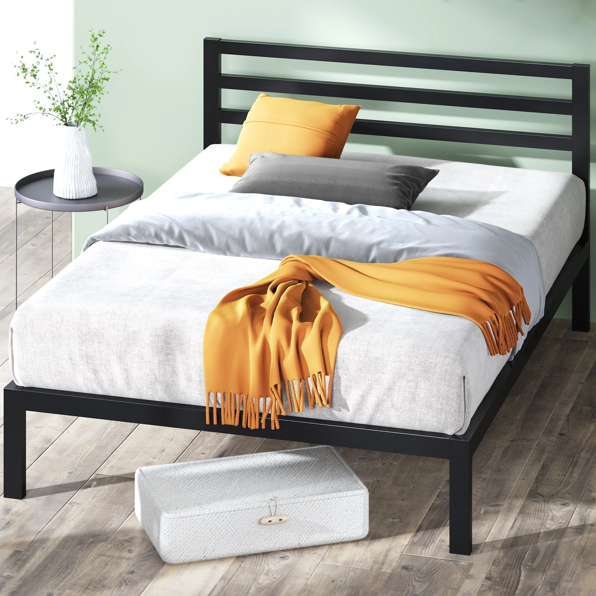 Tempat tidur modern dengan bingkai minimalis, bantal nyaman, dan selimut lemparan. Meja samping kecil memegang vas dengan tanaman hijau, sempurna untuk dekorasi kamar tidur yang bergaya