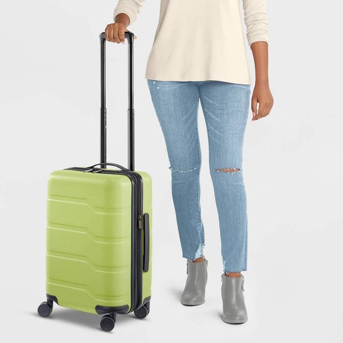 model with a lime greenish carry-on suitcase with wheels