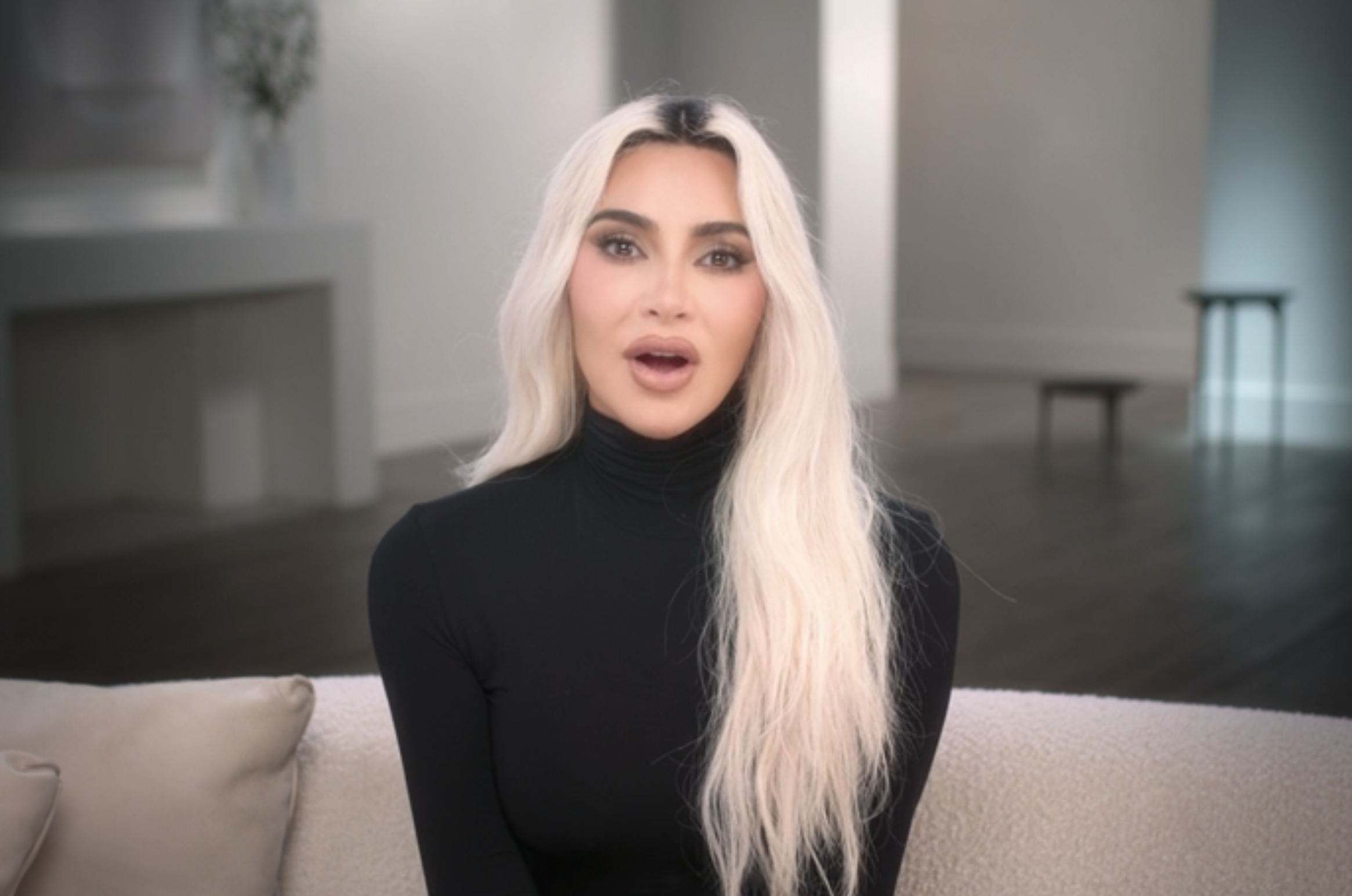Kim K speaking directly at the camera, seated in a modern living room setting