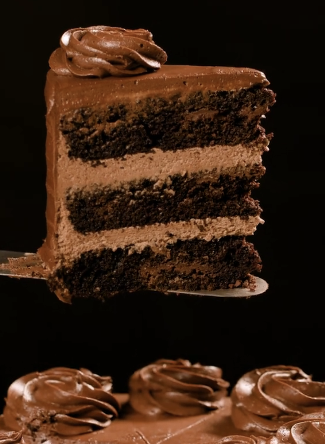 A portion    of decadent layered cocoa  barroom   with creamy frosting, being lifted from a decorated cake