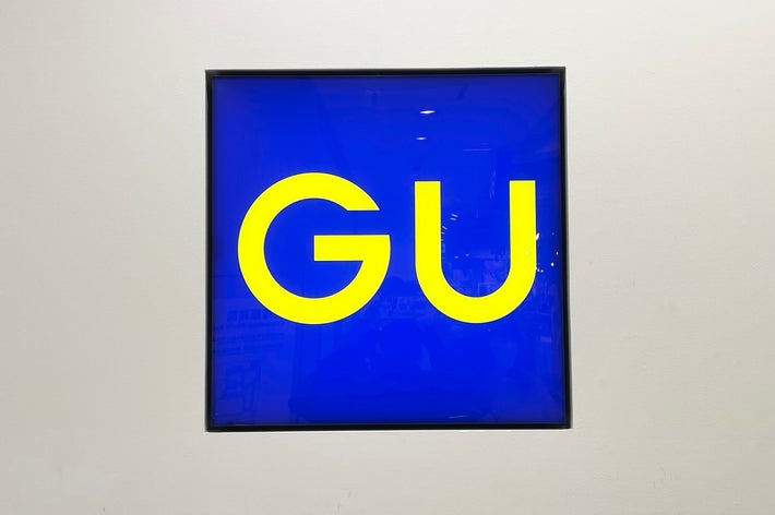 Sign with bold letters &ldquo;GU&rdquo; on a plain background