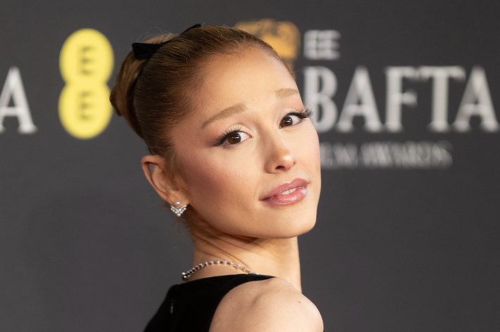 女性が黒いエレガントなドレスを着て、イベントのフォトコールでポーズをとっている。