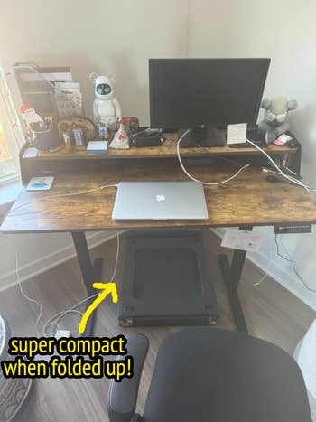 Minimalist wooden desk setup with laptop, monitor, and gadgets. A foldable treadmill is placed under the desk. Text highlights its compactness