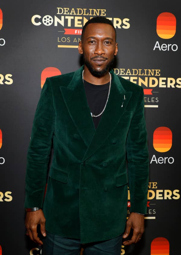 Man in a velvet jacket on a red carpet at a Deadline Contenders event
