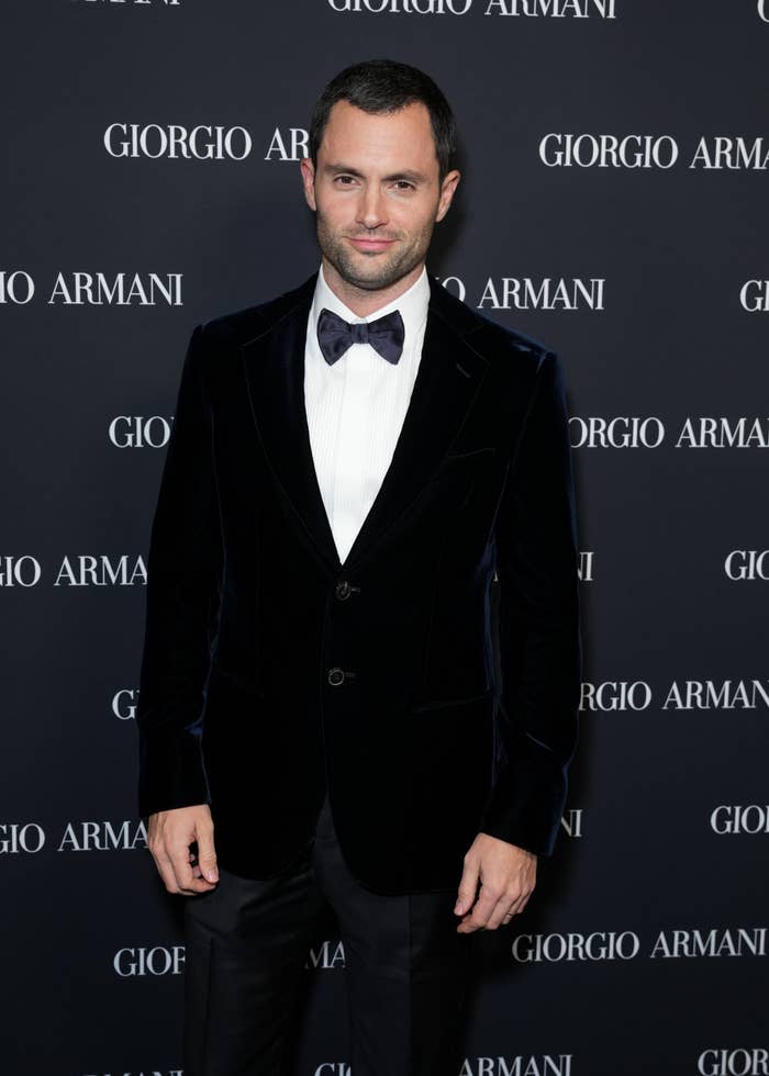Man in a sleek suit with a bow tie poses at a Giorgio Armani event backdrop