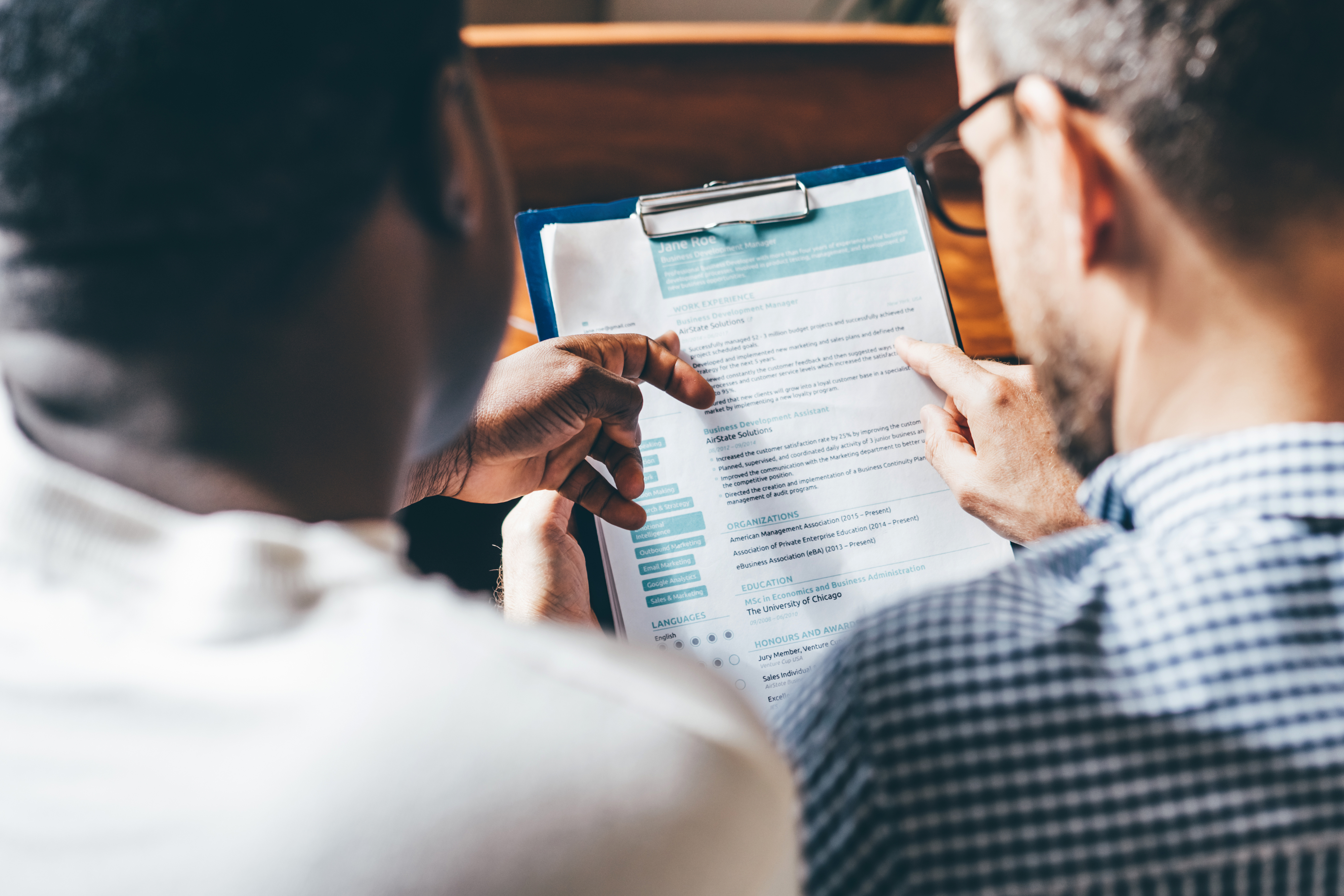 Two people reviewing a document on a clipboard, focusing on the content
