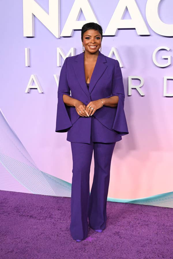 Person wearing a stylish purple pantsuit on a red carpet at a celebrity event