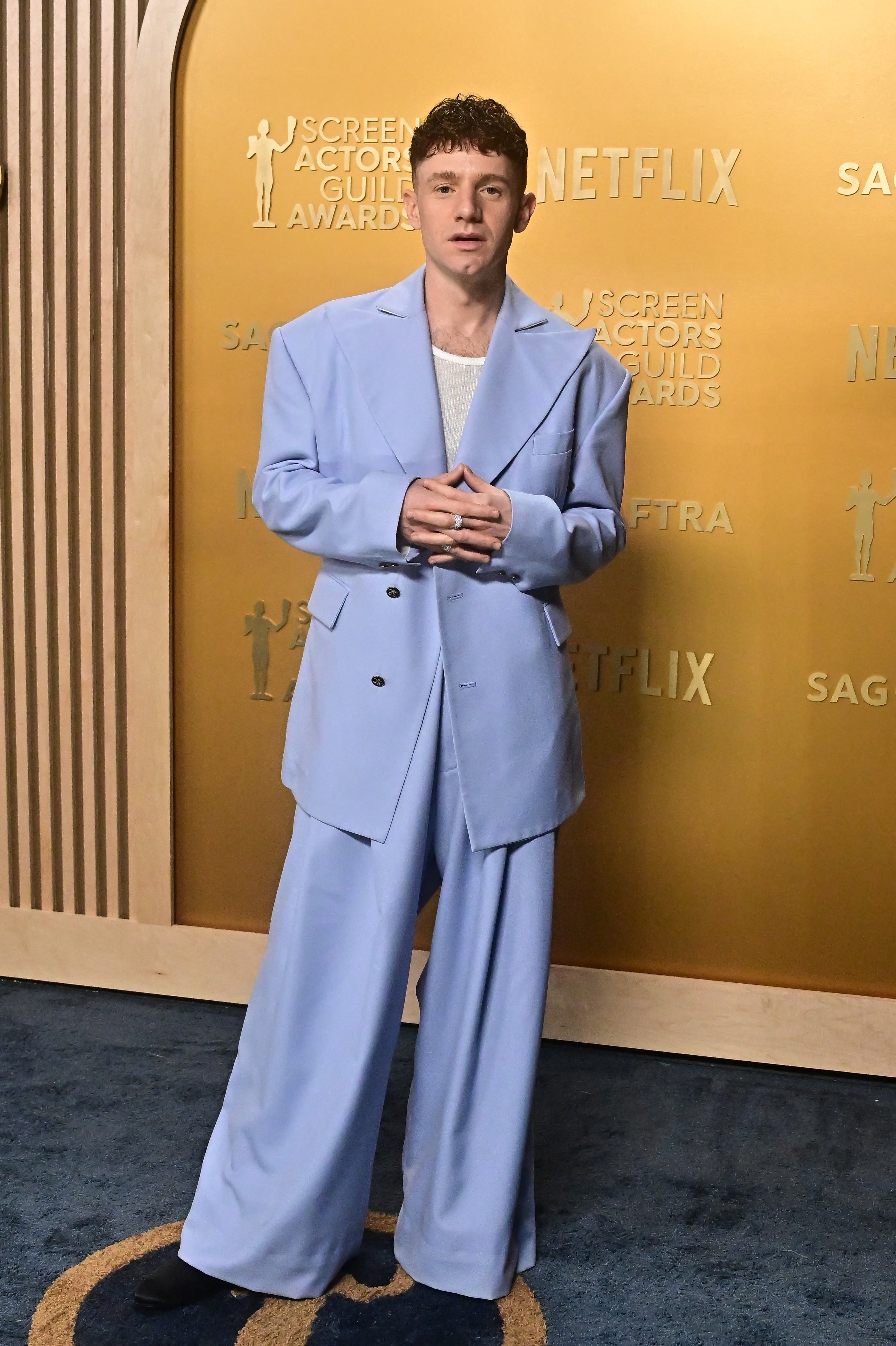 Person in oversized suit poses on SAG Awards red carpet