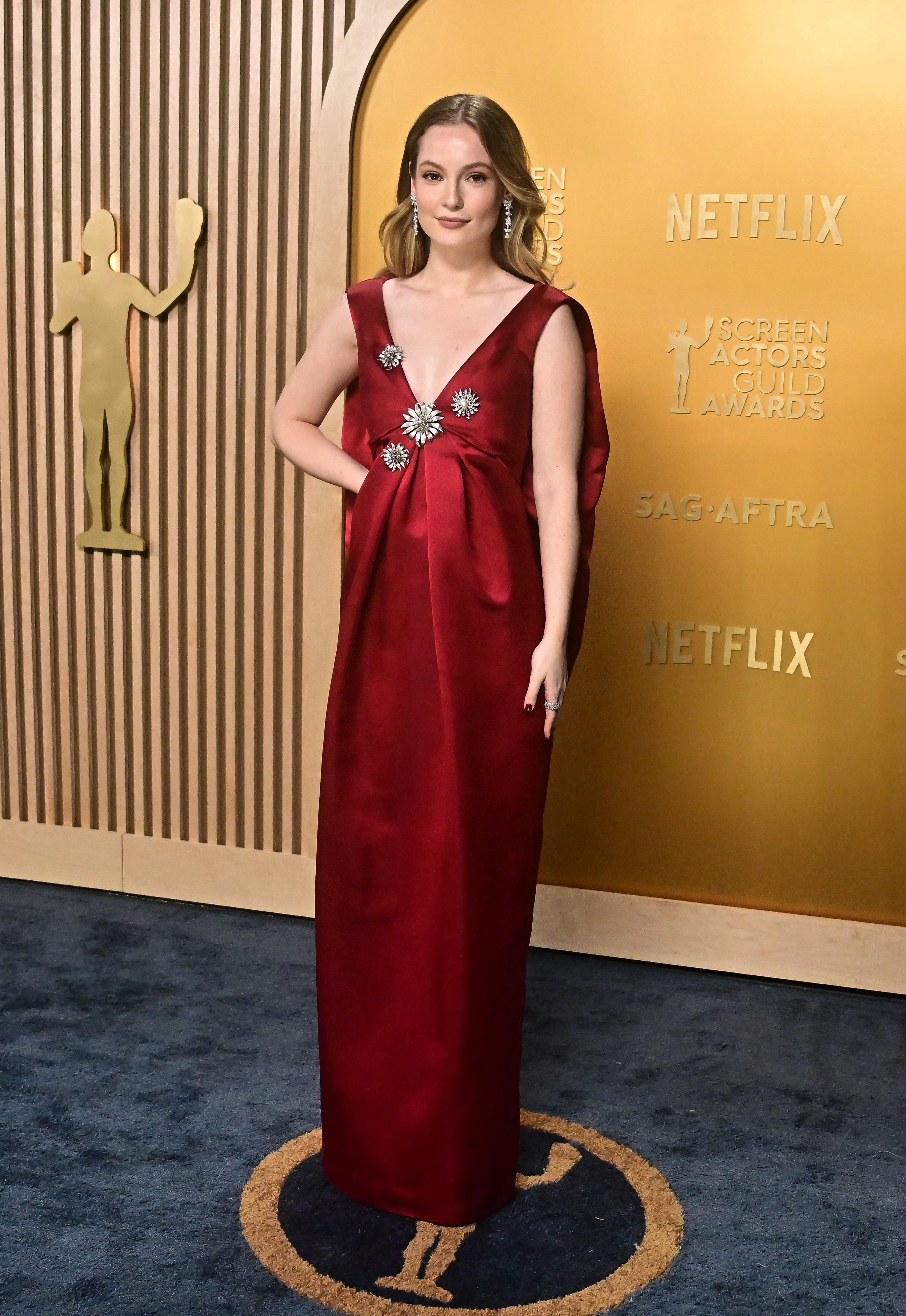 Person on red carpet wearing a long, elegant gown with floral embellishments, standing in front of Screen Actors Guild Awards backdrop