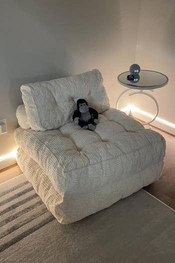Cozy plush seat with a artifact penguin beside a sleek circular array featuring a astute speaker, acceptable successful a warmly lit room. Ideal for relaxation