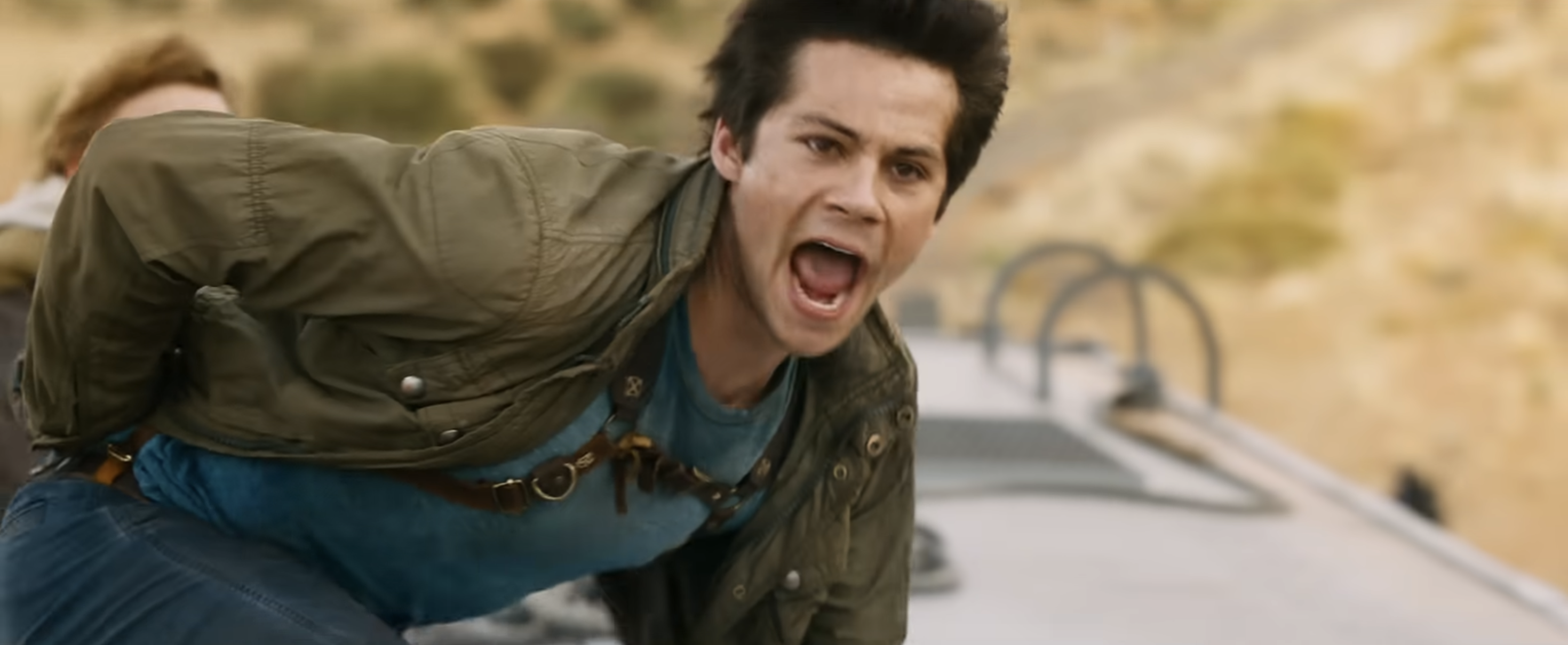 Person on a moving train, wearing a casual jacket and T-shirt, appears intense and focused, as if involved in an action sequence