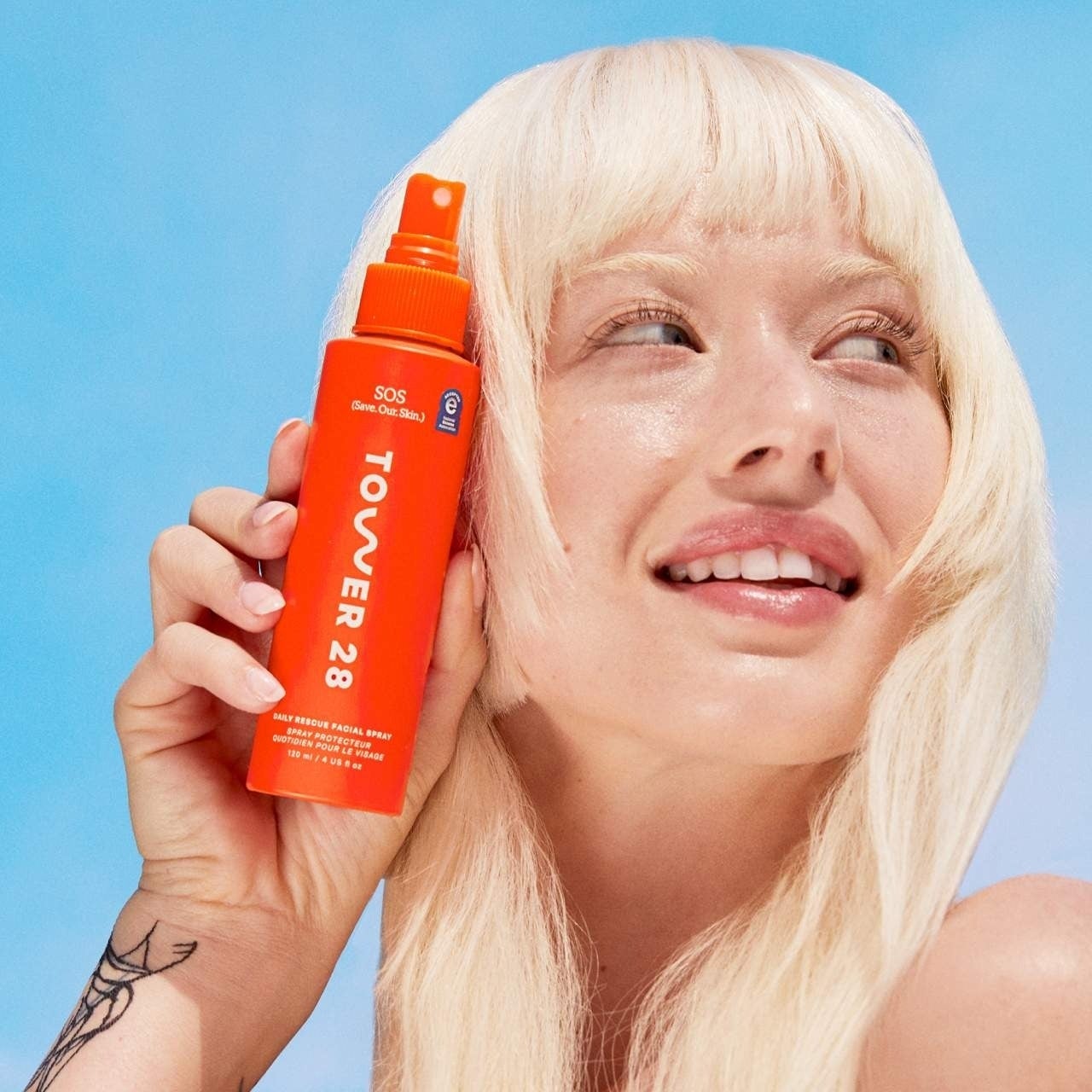 Person holding a Tower 28 SOS skincare spray bottle