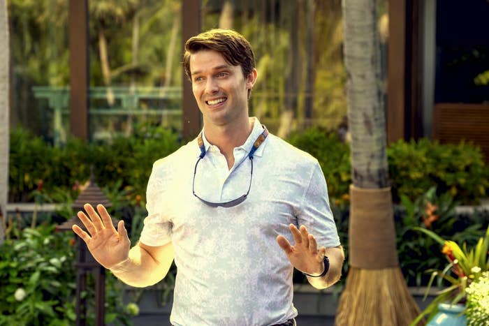 Man outdoors smiling, wearing casual floral shirt and sunglasses around his neck