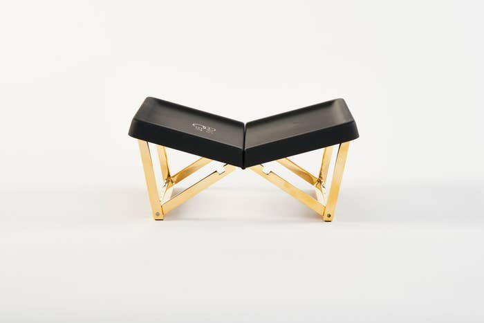 A modern, black and gold folding stool with a zigzag design