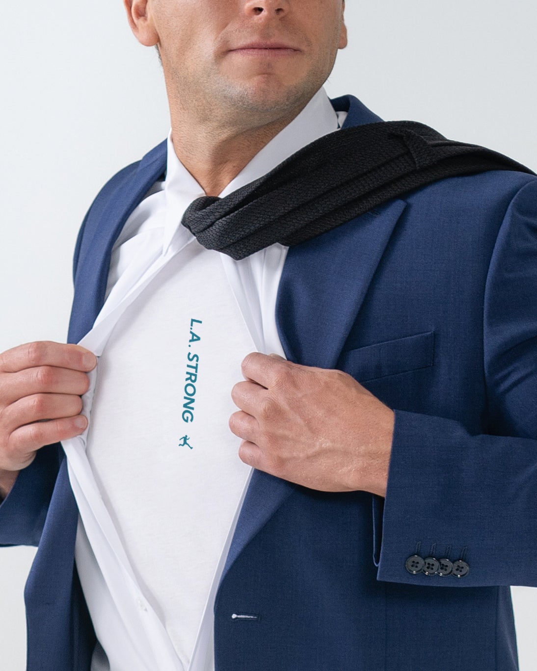 Person wearing suit reveals a shirt with "LA STRONG" text, resembling a superhero pose