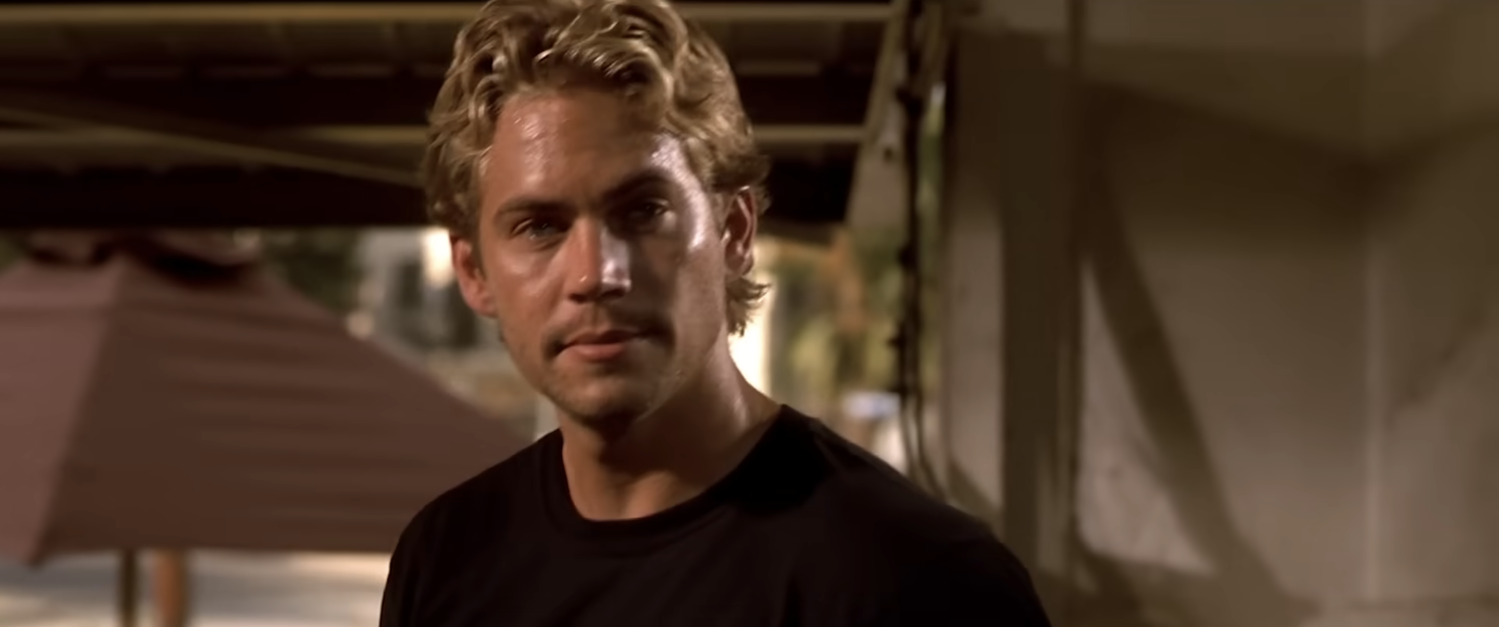 Man with short wavy hair wearing a simple shirt, standing outdoors, looking ahead