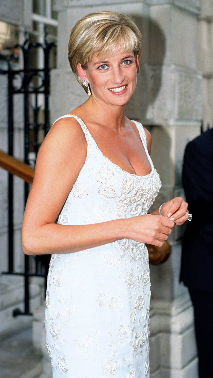 I don’t know who this is, but the person is wearing an elegant sleeveless gown with intricate detailing, posing outdoors