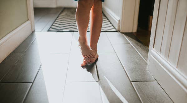 Child walking down a sunlit hallway on a zigzag-patterned rug