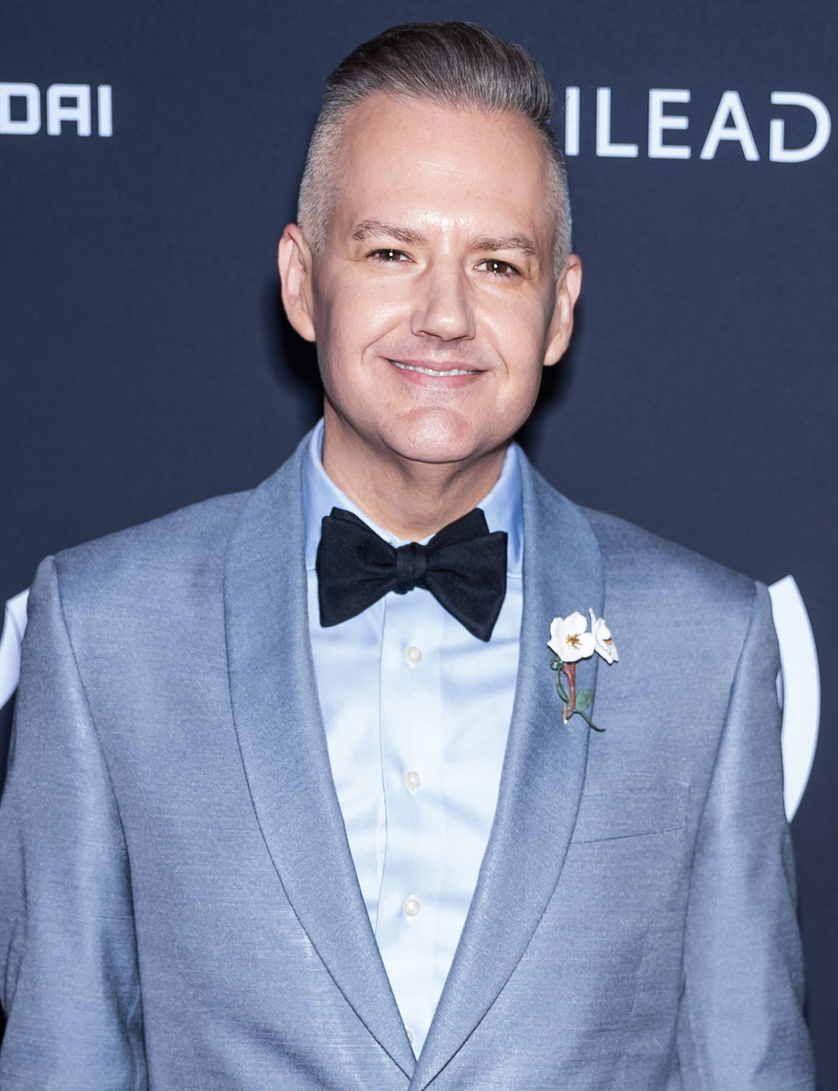 Person successful  a stylish suit   with a bow necktie  and floral lapel pin astatine  a ceremonial  event