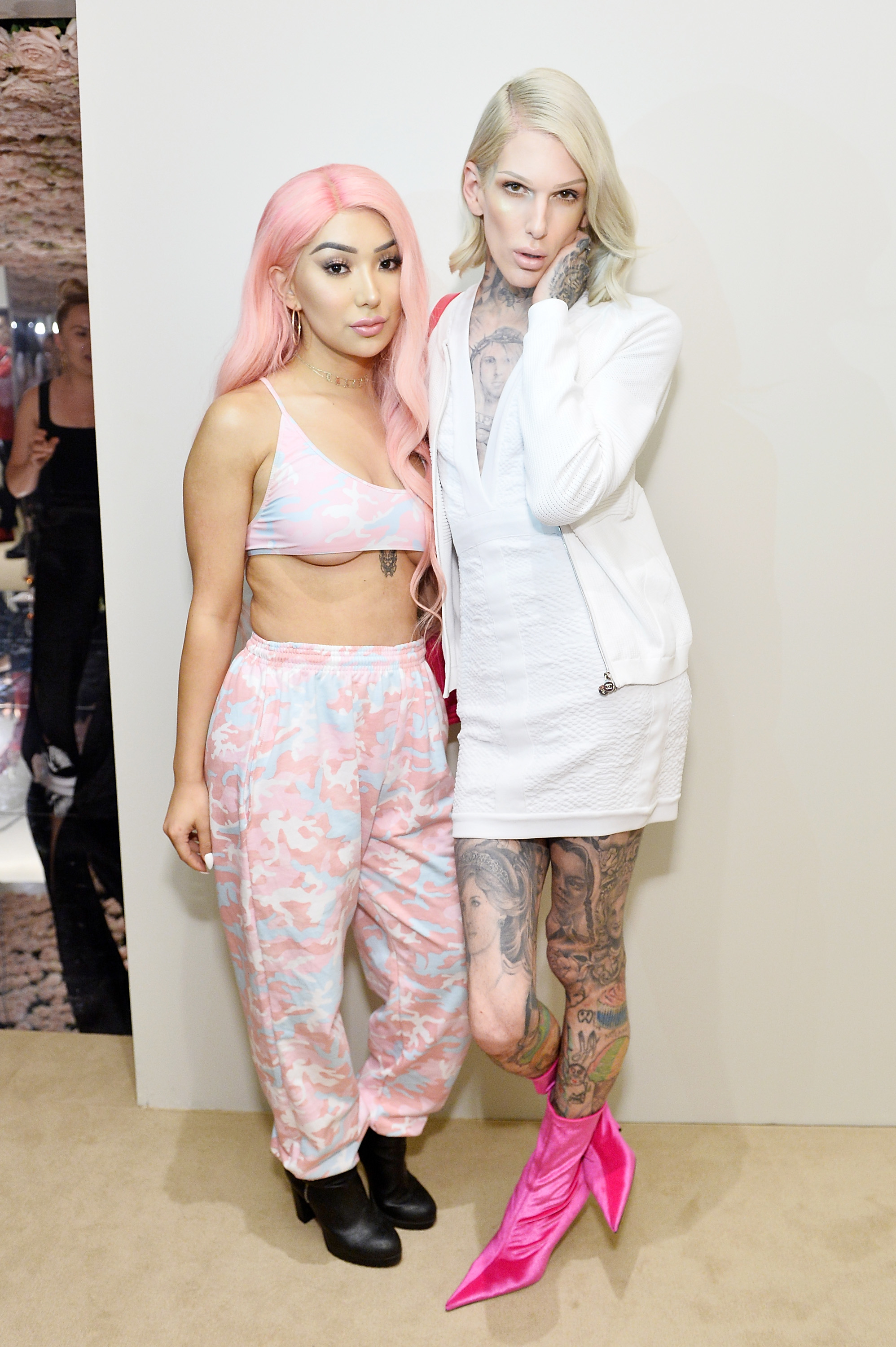 Two individuals connected  a reddish  carpet. One wears a pastel sports bra and pants, portion    the different   wears a achromatic  outfit with vibrant pinkish  boots