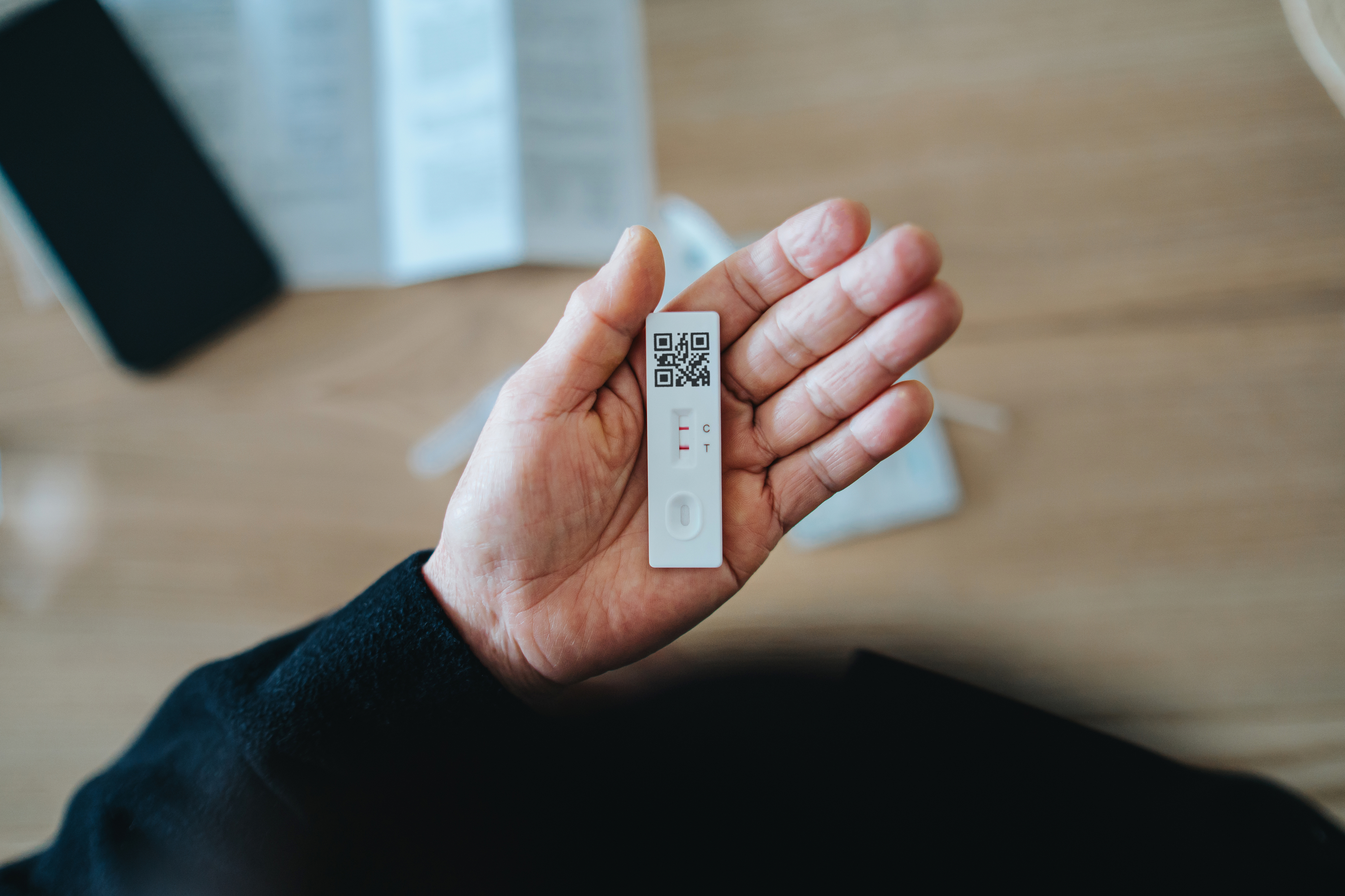 En person har en hurtig test fra Covid-19 som viser negative resultater, med en QR-kode synlig på testen