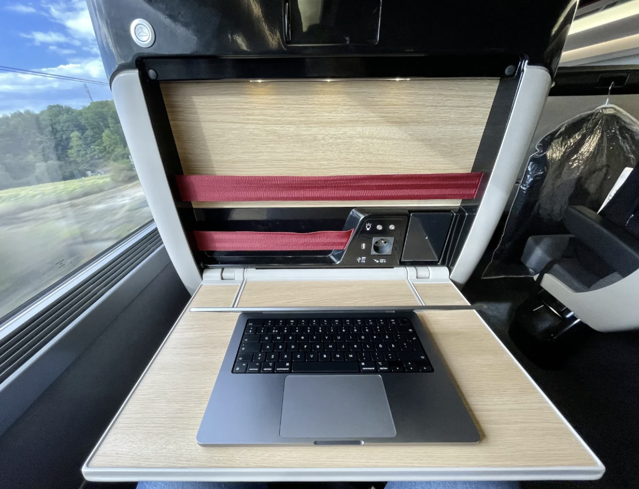 Laptop connected  a woody  tray array  successful  a train, adjacent  to a model   presumption    of greenery and a suit   hanging connected  the side