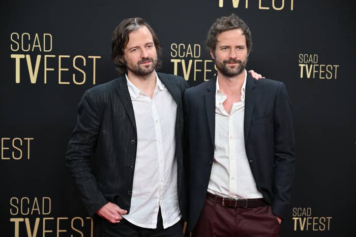 Matt Duffer and Ross Duffer at SCAD TVFest, both in blazers with open-collared shirts, posing together against a backdrop
