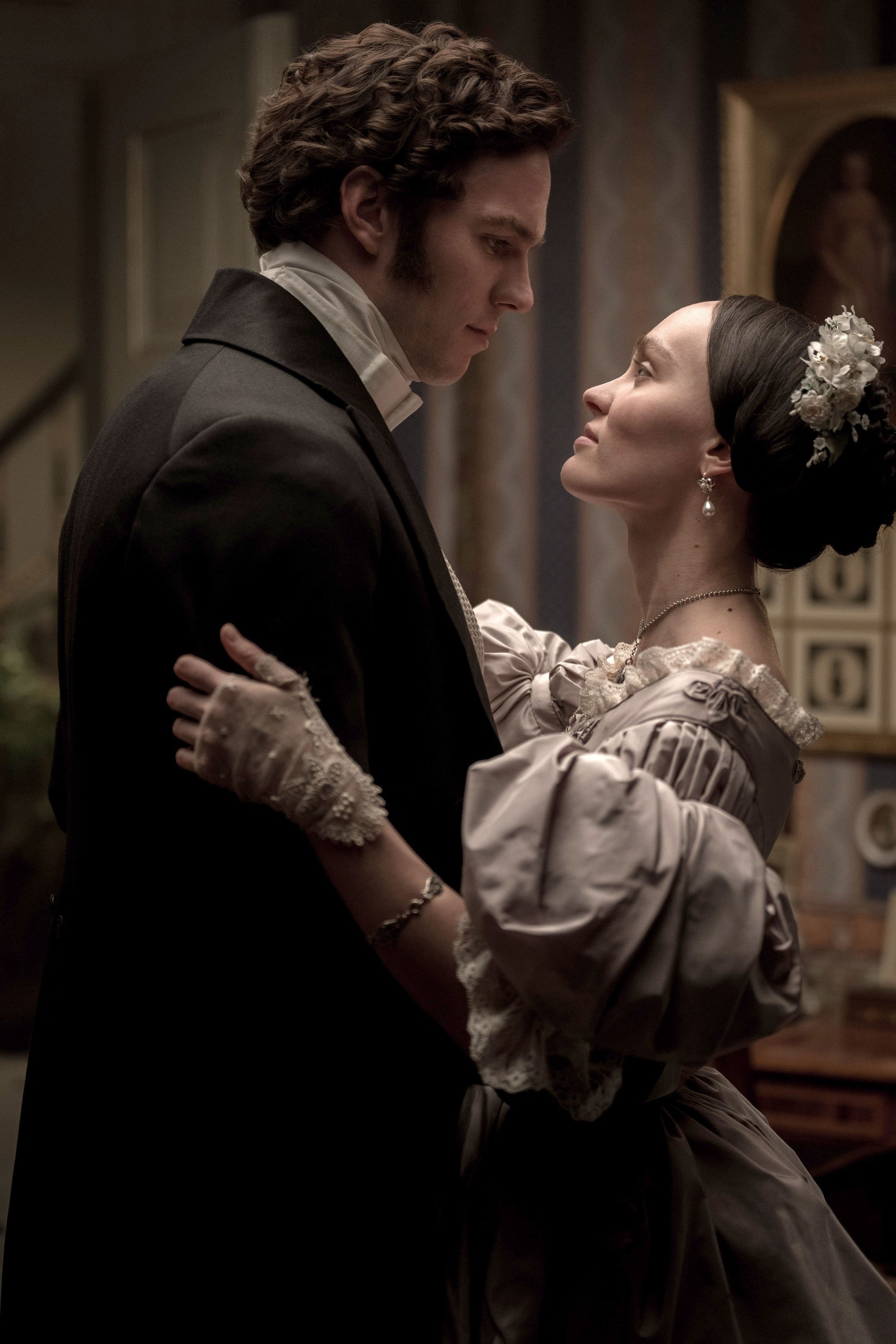 A couple in vintage attire gazes at each other intimately, evoking a historical romance scene