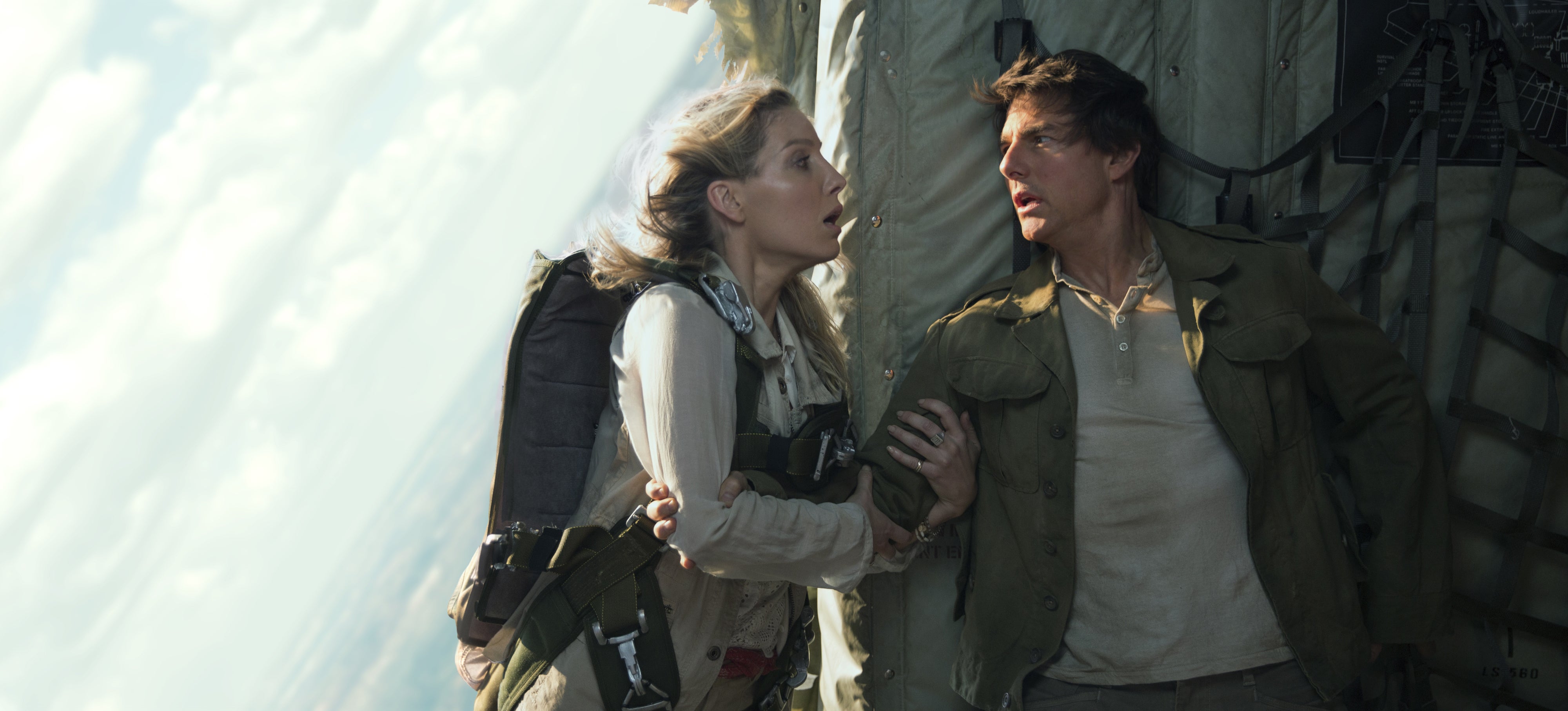 Two people in action scene on a tilting aircraft, with intense expressions and military-style outfits