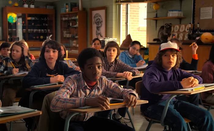 Classroom scene with students sitting at desks, attentively looking forward. The setting seems to be a typical school environment