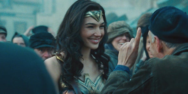 Person in a warrior costume with a crown, smiling in a crowd of people wearing casual and military-style clothing