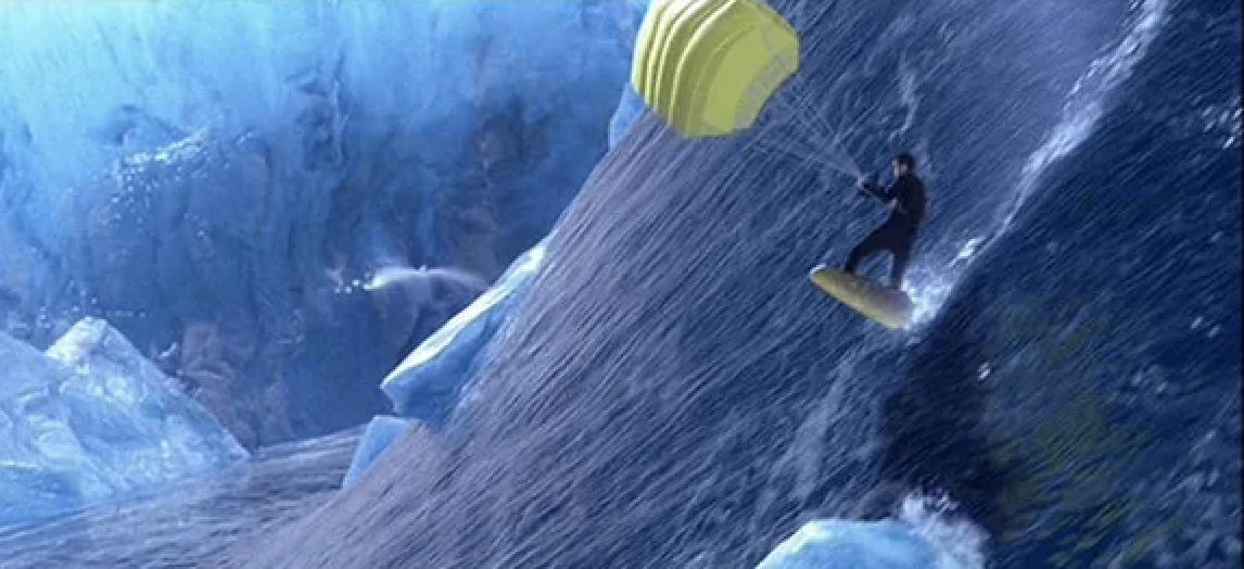 Person parasailing on a large wave with a yellow chute, surrounded by icy cliffs and splashing water
