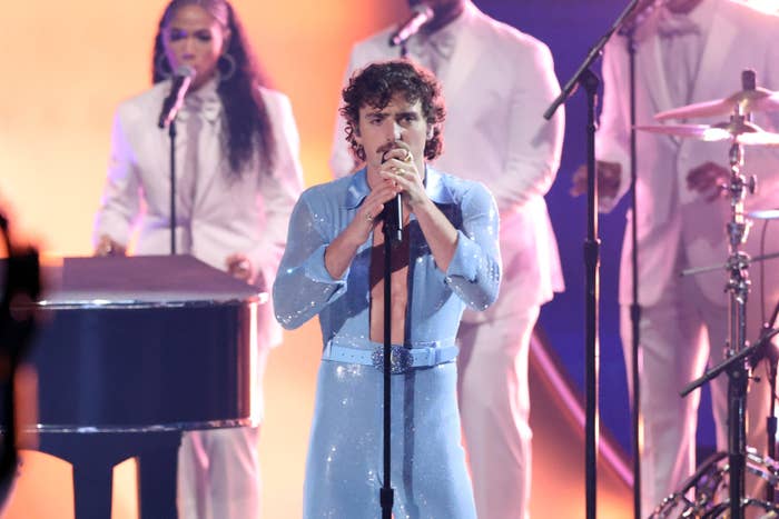 Benson Boone performs on stage in a sparkling outfit, accompanied by backup singers and musicians