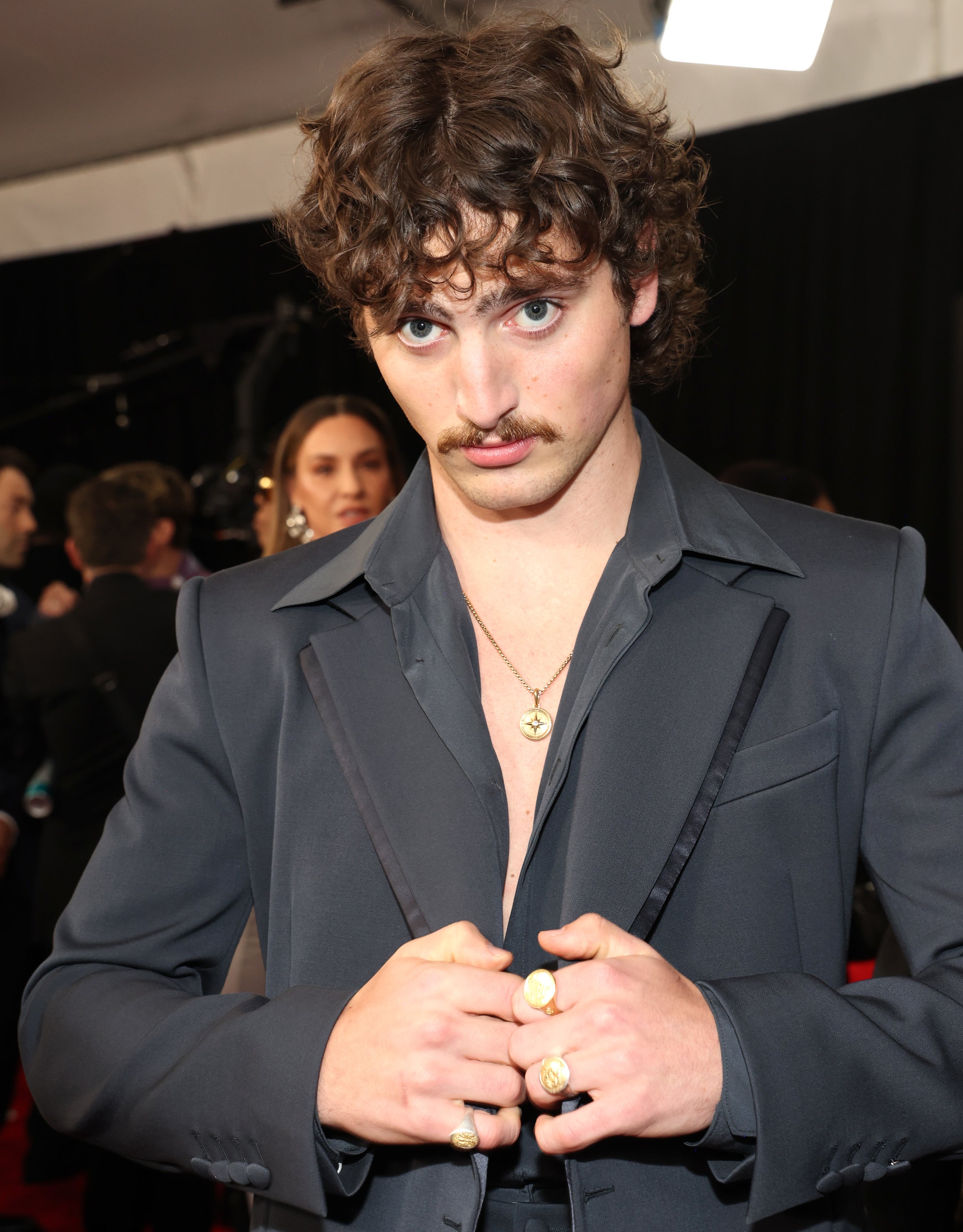 Benson Boone in tailored suit with open collar and gold jewelry on a red carpet event