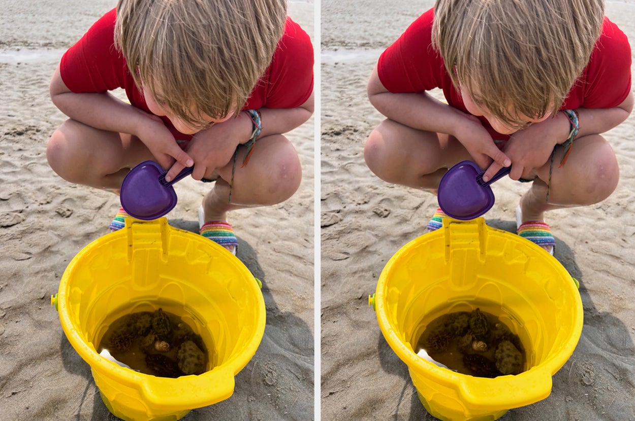 Child with a backpack stands on a sandy beach, facing the sea