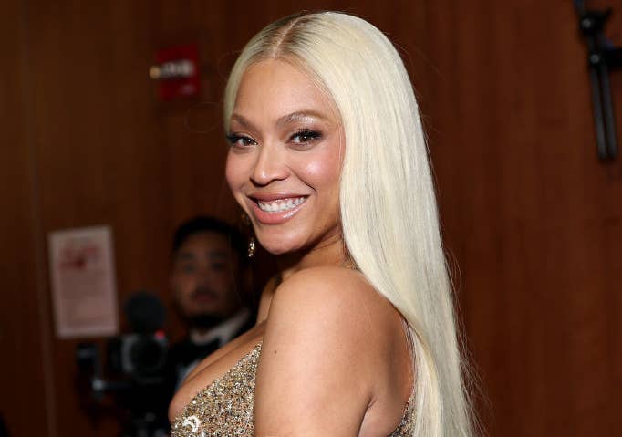 Celebrity in an elegant, sequined off-the-shoulder gown with intricate patterns, smiling at an event