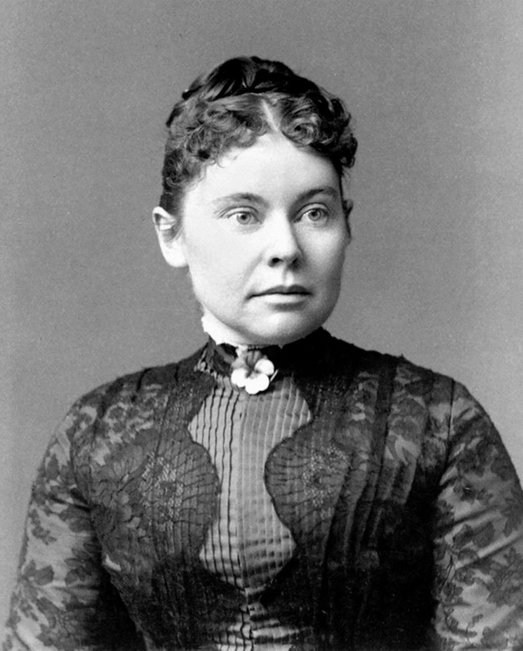A vintage photo of a woman with curly hair in an ornate high-neck dress, exuding a formal, poised expression