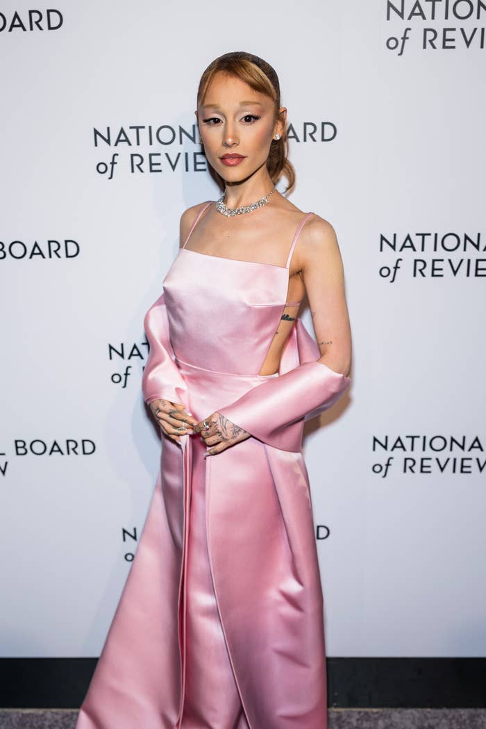 Ariana Grande in an elegant, sleeveless satin gown on a red carpet at an event with