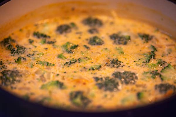 Broccoli cheese soup in a pot, showing broccoli florets in a creamy, cheesy broth