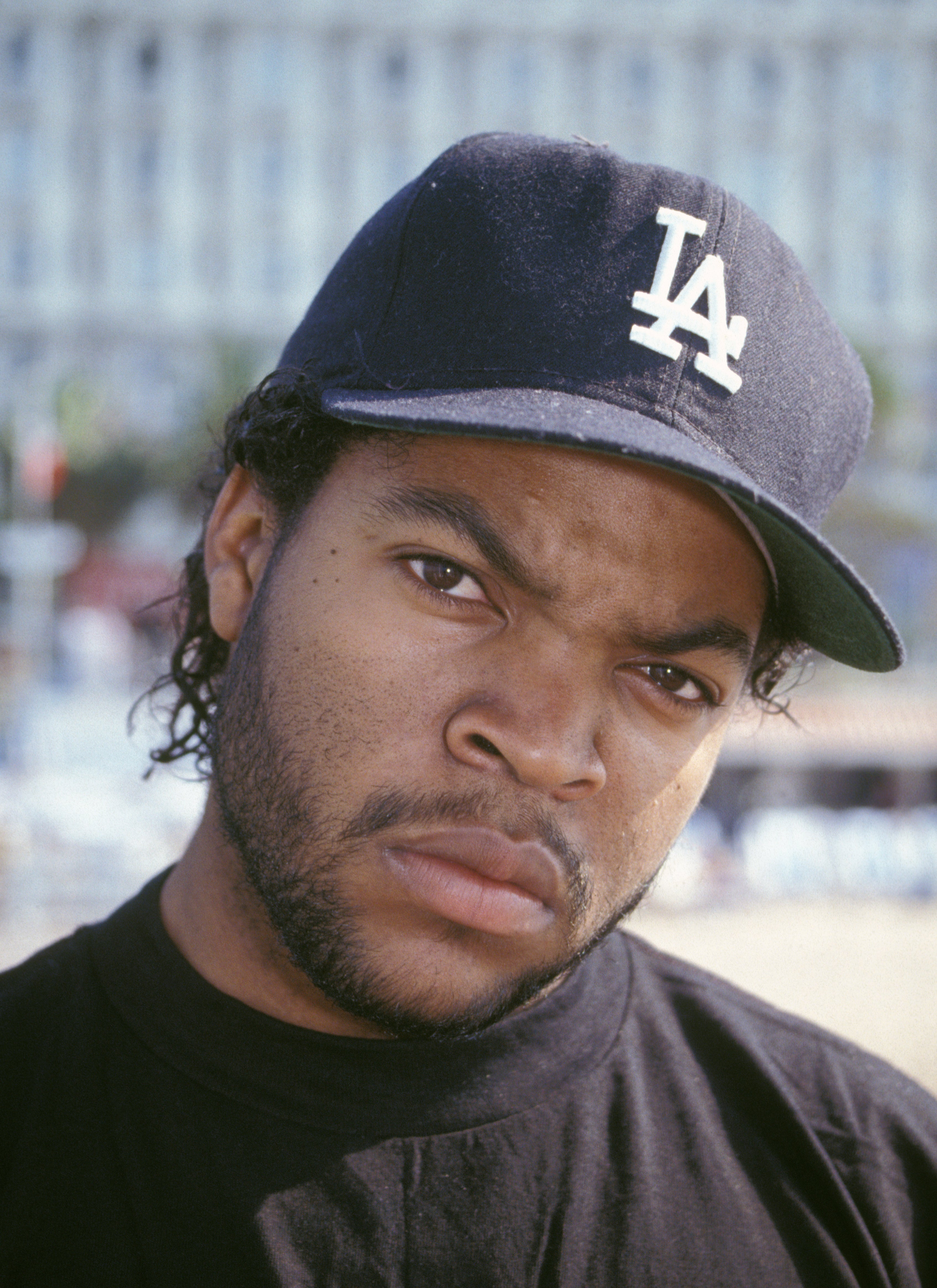 Person wearing a baseball cap with &quot;LA&quot; logo, looking directly at the camera outdoors