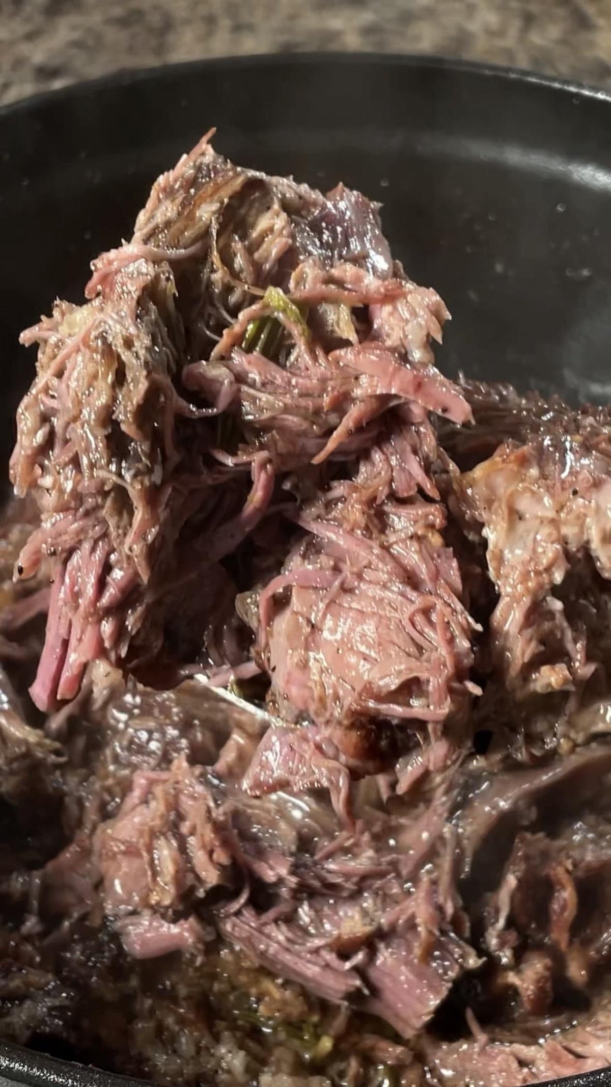 Tender shredded beef in a pan, showcasing juicy, cooked texture, ideal for an article about savory recipes or cooking techniques