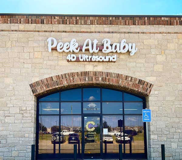Front view of &quot;Peek At Baby 4D Ultrasound&quot; clinic with stone exterior. Accessible parking is visible