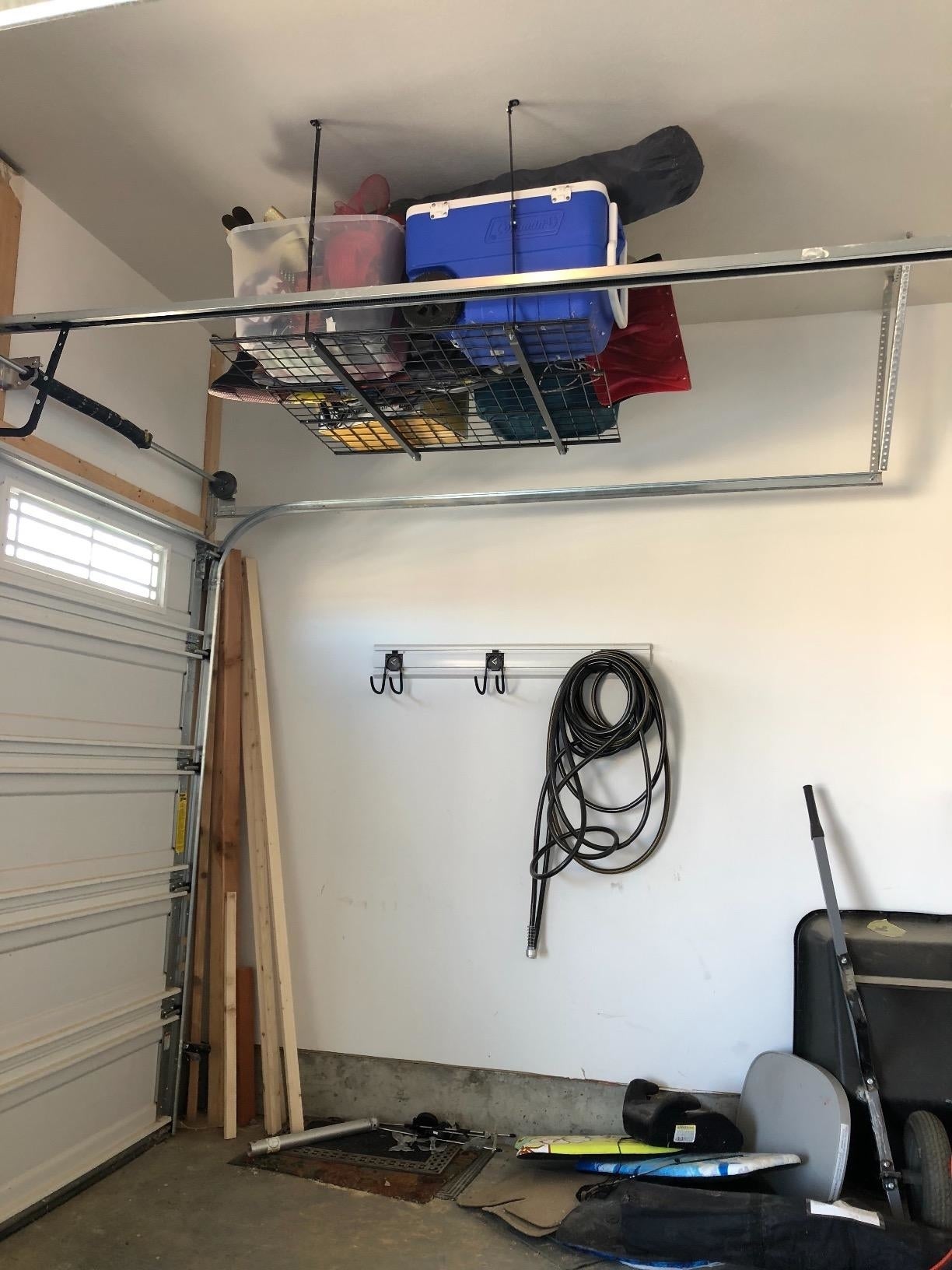 reviewer's garage with organized overhead storage: boxes on ceiling rack, coiled hose and tools on wall hooks, clear floor space