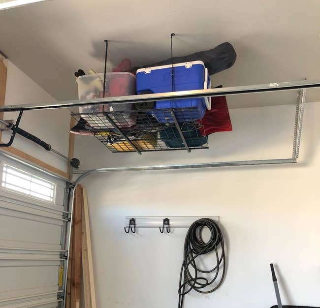 reviewer's garage with organized overhead storage: boxes on ceiling rack, coiled hose and tools on wall hooks, clear floor space