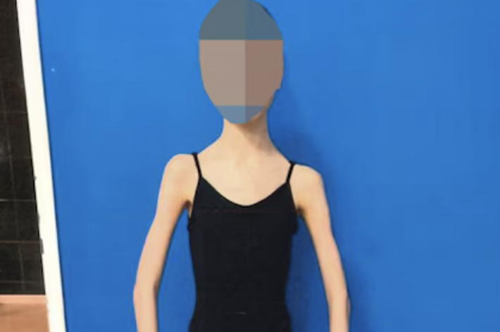 バレエの衣装を着た人物がポーズをとっています。背景はシンプルです。