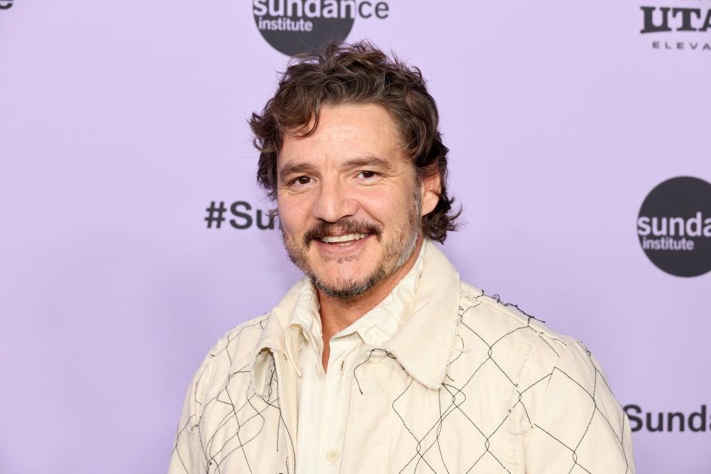 Man in an embroidered jacket smiling at Sundance event backdrop
