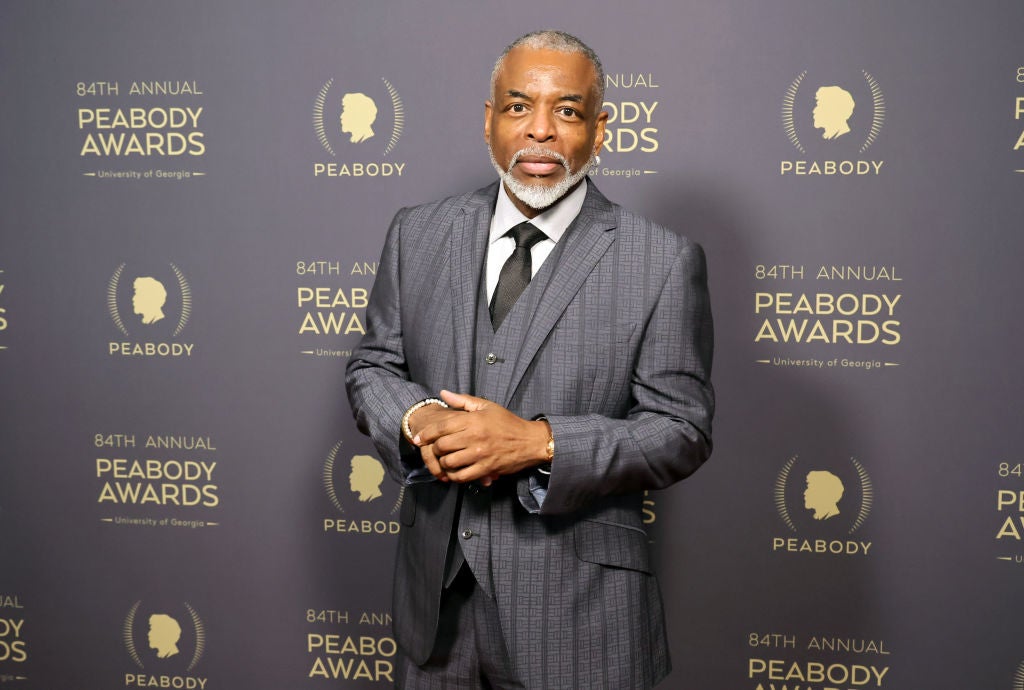 Man in a tailored suit poses at the 84th Annual Peabody Awards backdrop