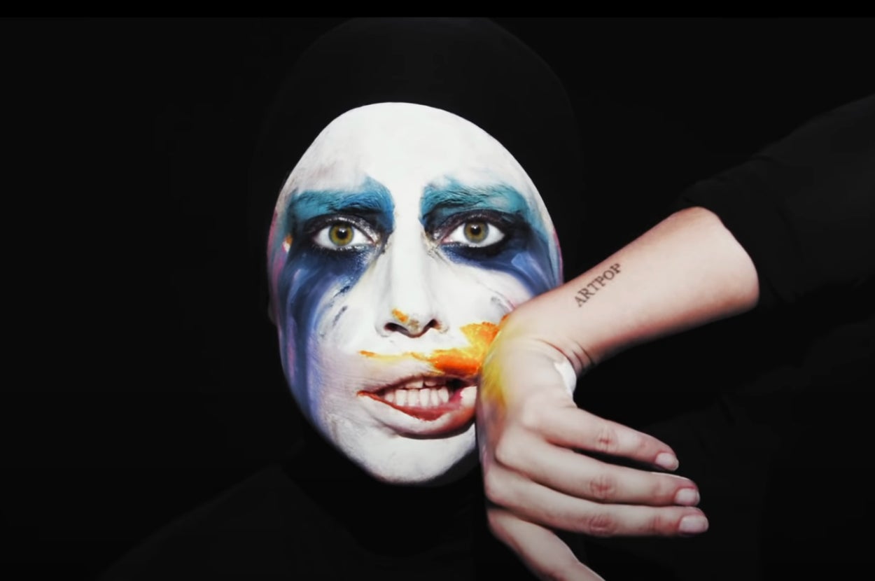 Lady Gaga wiping paint on her face in the Applause music video