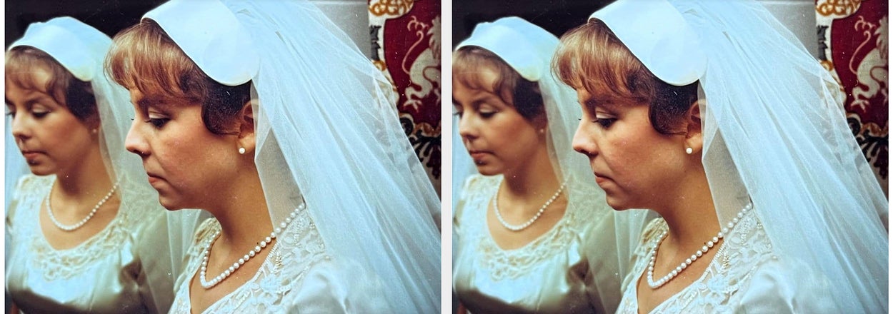 Bride in lace dress and veil, pearl necklace, and matching hairpiece looks down, reflected in a mirror. Elegant and serene pose