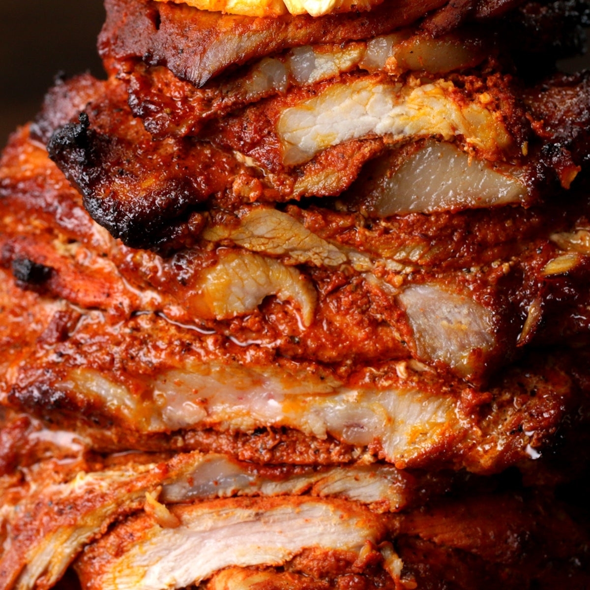 Closeup of stacked layers of seasoned, roasted meat, showing succulent textures and crispy edges